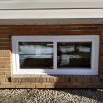 basement window installed on home with brick exterior